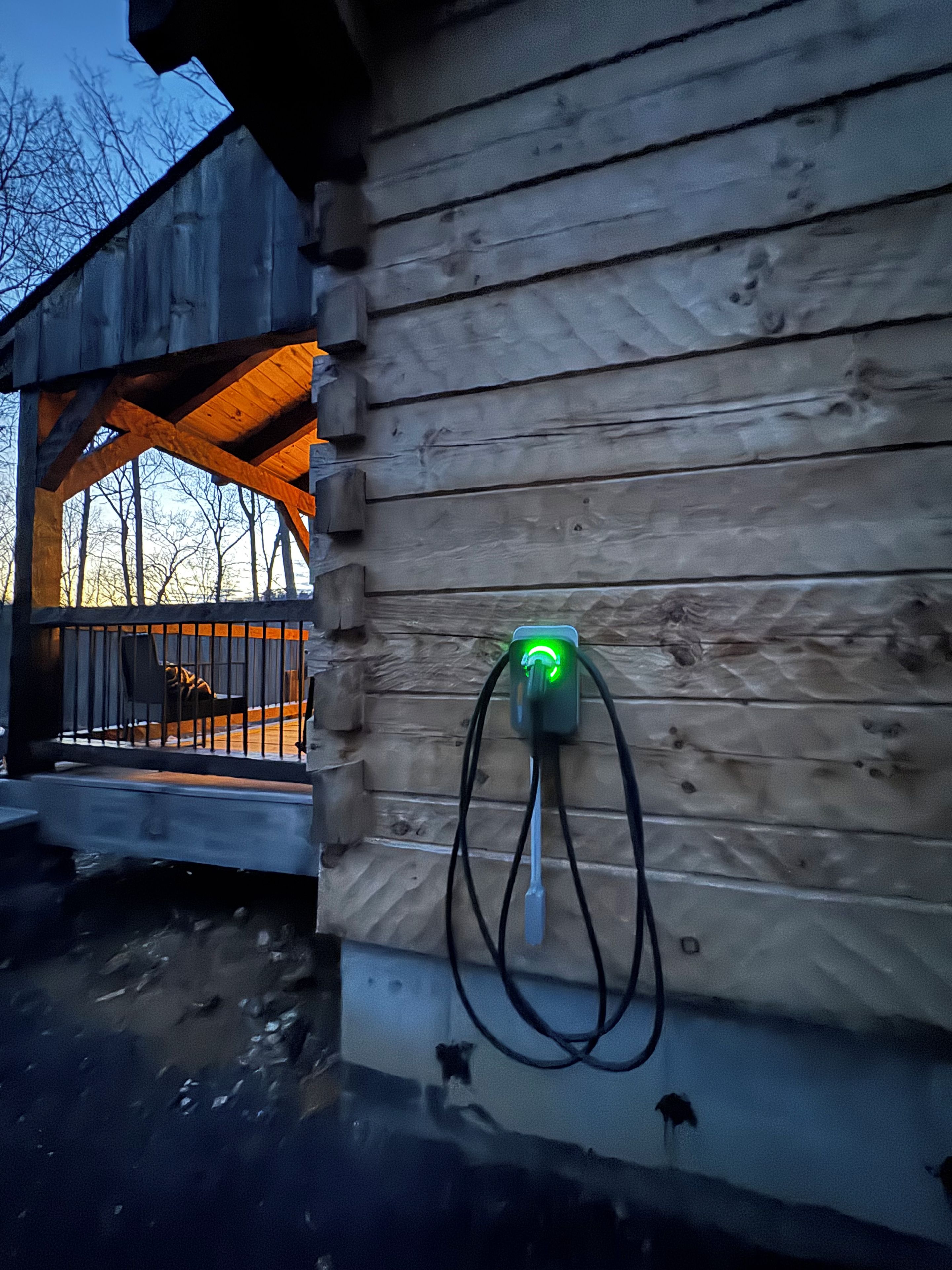 Una cabaña de madera con un enchufe verde fijado en la pared exterior.