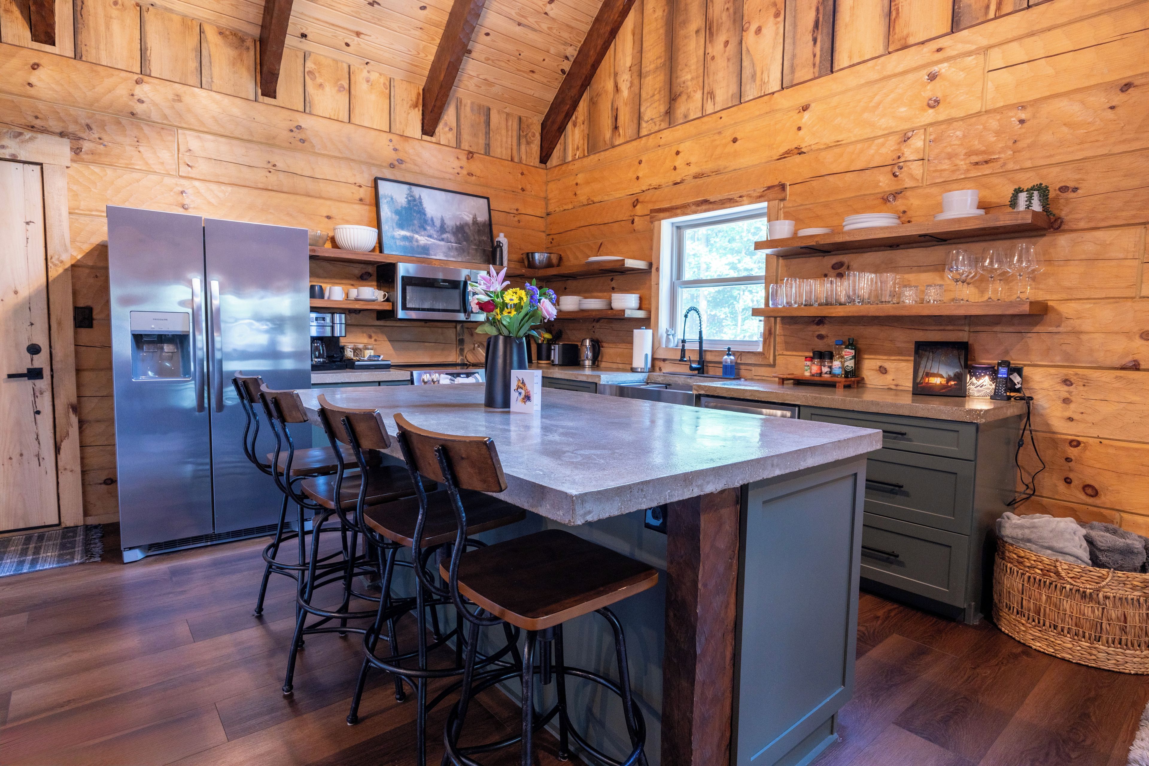 A wooden cabin interior with a kitchen, bar area, and seating.