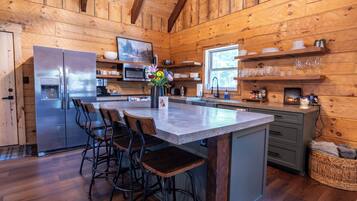 A wooden cabin interior with a kitchen, bar area, and seating.