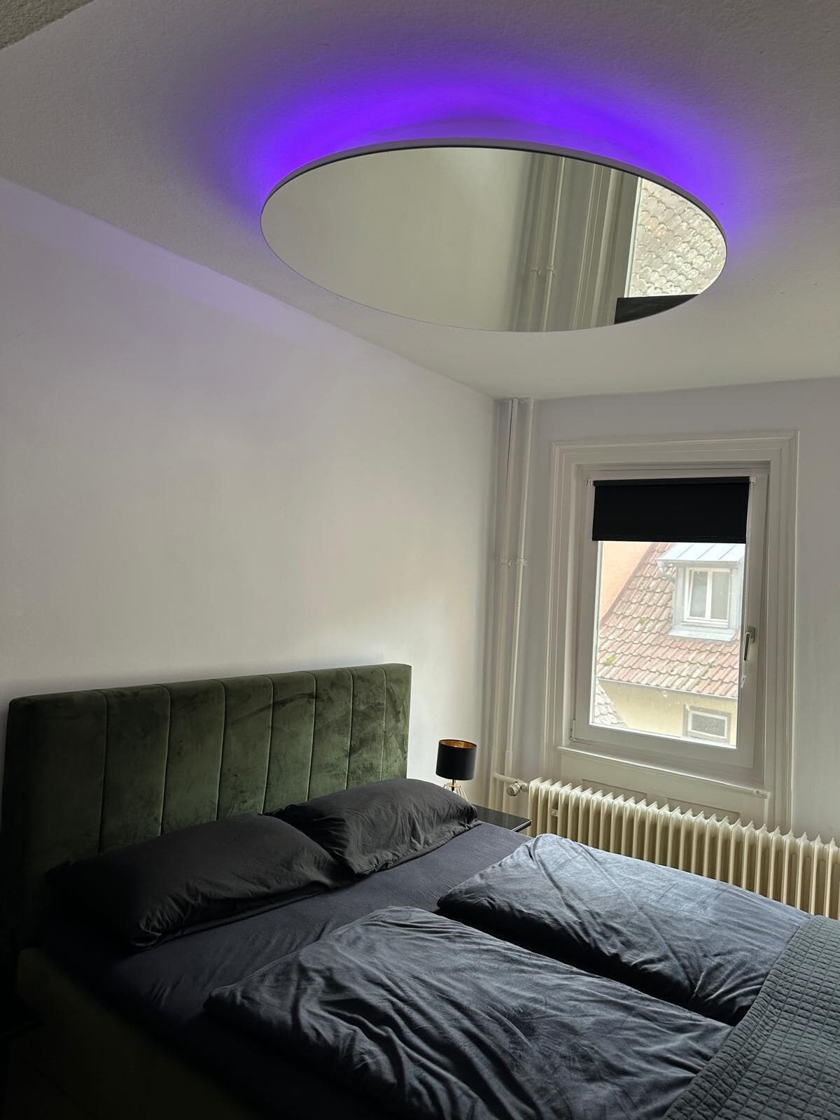 A bedroom with a bed, a window, and a circular ceiling light fixture.