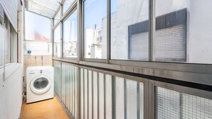 A narrow laundry room with a washing machine, large windows, and a view of buildings outside. - Warm and cozy apartment for two in Palermo (CABA)