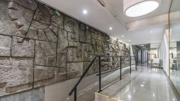 A modern interior with a stone wall, a staircase with metal railings, and a bright ceiling light. - Warm and cozy apartment for two in Palermo (CABA)