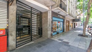 A street view with a closed shop, a blue storefront, and a tree on the sidewalk. - Warm and cozy apartment for two in Palermo (CABA)