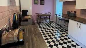Une cuisine avec un sol à carreaux noirs et blancs, un plan de travail en bois et un coin repas comprenant une table et des chaises.