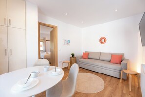 A modern living room with a dining area, a sofa, and a small side table. - AeroHill Suites Near Athens Airport By SEM (Spata-Artemida)