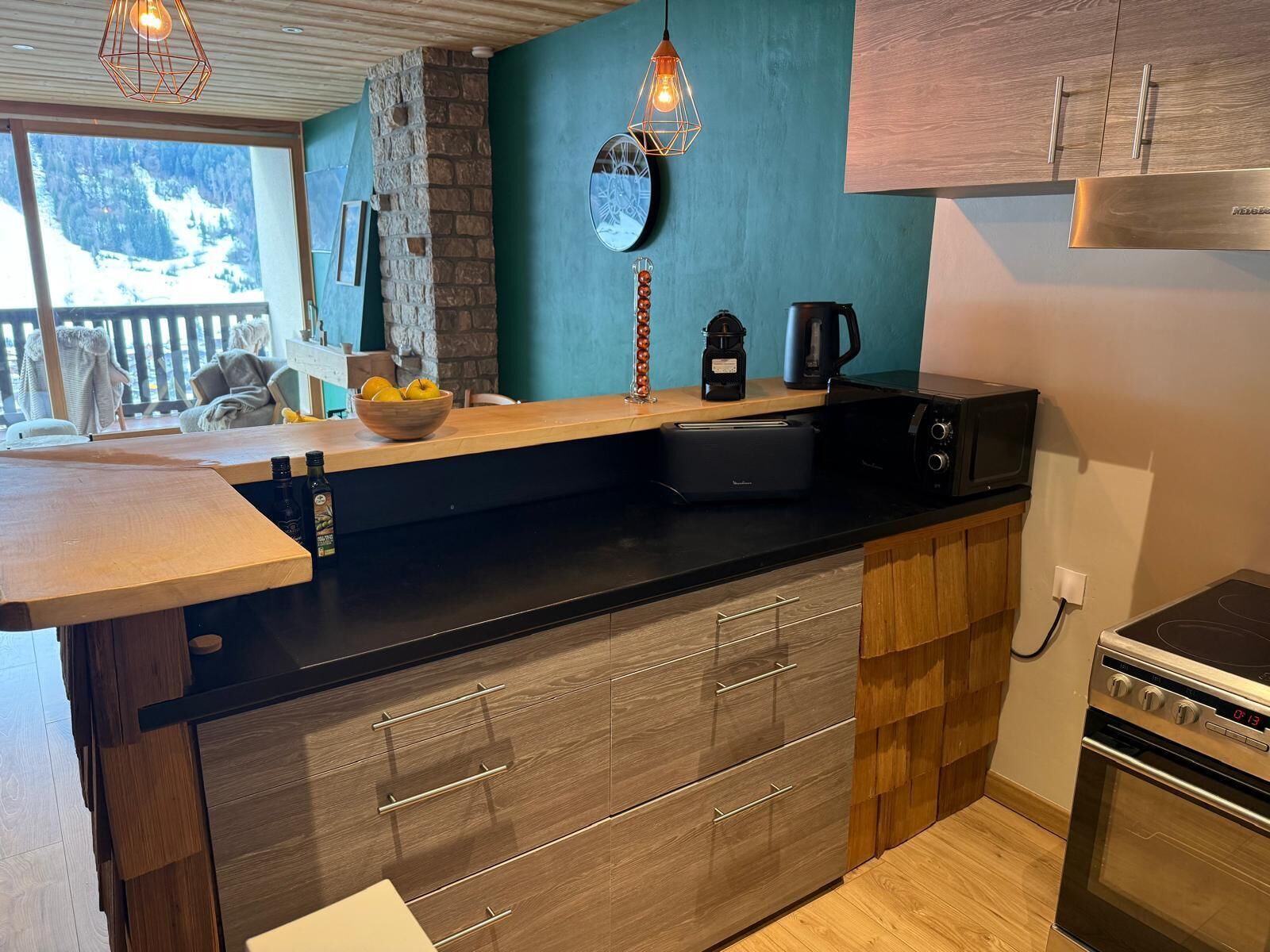Una cocina moderna con un detalle de pared de piedra, armarios de madera y horno empotrado.