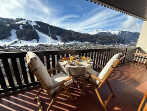 Een balkon met een ontbijt-eettafel, met uitzicht op een besneeuwde stad.