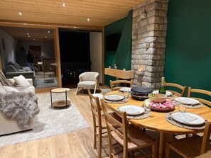 Een eetgedeelte met een houten tafel voor vier personen, omringd door houten stoelen. Op de achtergrond is een stenen muur en een balkon met uitzicht te zien.