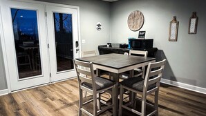 Un comedor con mesa y sillas de madera, una barra de café y un reloj en la pared.