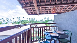 A balcony with a wooden railing, a table with plates and cutlery, and a hanging light fixture.