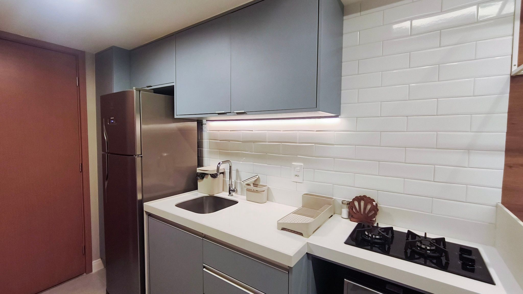 A compact kitchen with a refrigerator, sink, and stove.