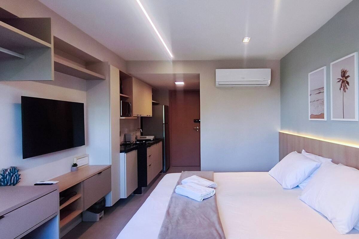 Una camera d'albergo con un letto, una TV, angolo cottura e condizionatore d'aria a parete.