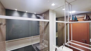 Ein modernes Badezimmer mit Duschkabine aus Glas, einem weißen Waschbecken und einer Holztür.
