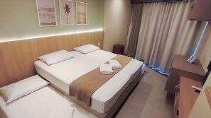 A hotel room with a large bed, a bedside table, a lamp, and a view of the sea through the window. - Atlântico Carneiros Beira-Mar (Tamandaré)