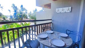 A balcony with a table set for four, chairs, and a wall-mounted artwork. - Atlântico Carneiros Beira-Mar (Tamandaré)