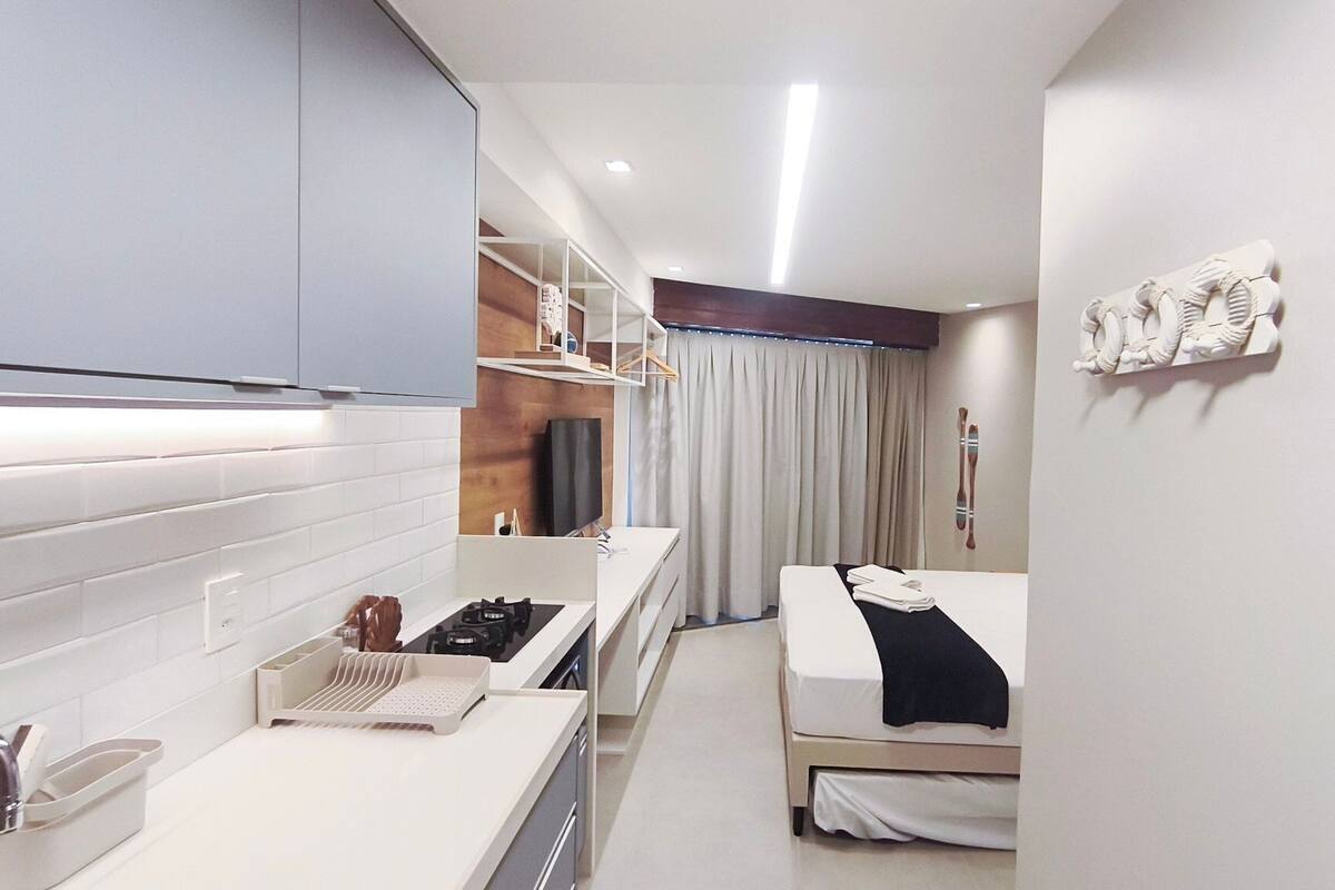Camera d'albergo compatta con angolo cottura, un letto, bagno e vista esterna.