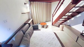 A modern interior with a sofa, a small round table, and a staircase. - Atlântico Carneiros Beira-Mar (Tamandaré)