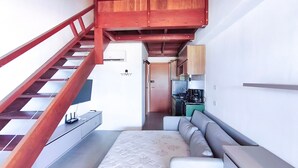 Un escalier menant à une chambre comprenant un lit, une kitchenette et un petit coin salon.