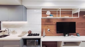 Eine moderne Küche mit Einbau-Mikrowelle, Gasherd und einem Flachbildfernseher, der an einer Holzwand angebracht ist.