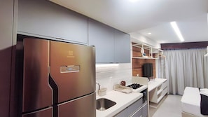 A modern kitchen with a stainless steel refrigerator, white countertops, and a built-in oven.