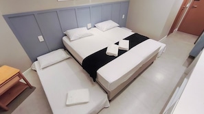 Ett hotellrum med två separata sängar, ett nattduksbord i trä och en stor säng med ett svart överkast.