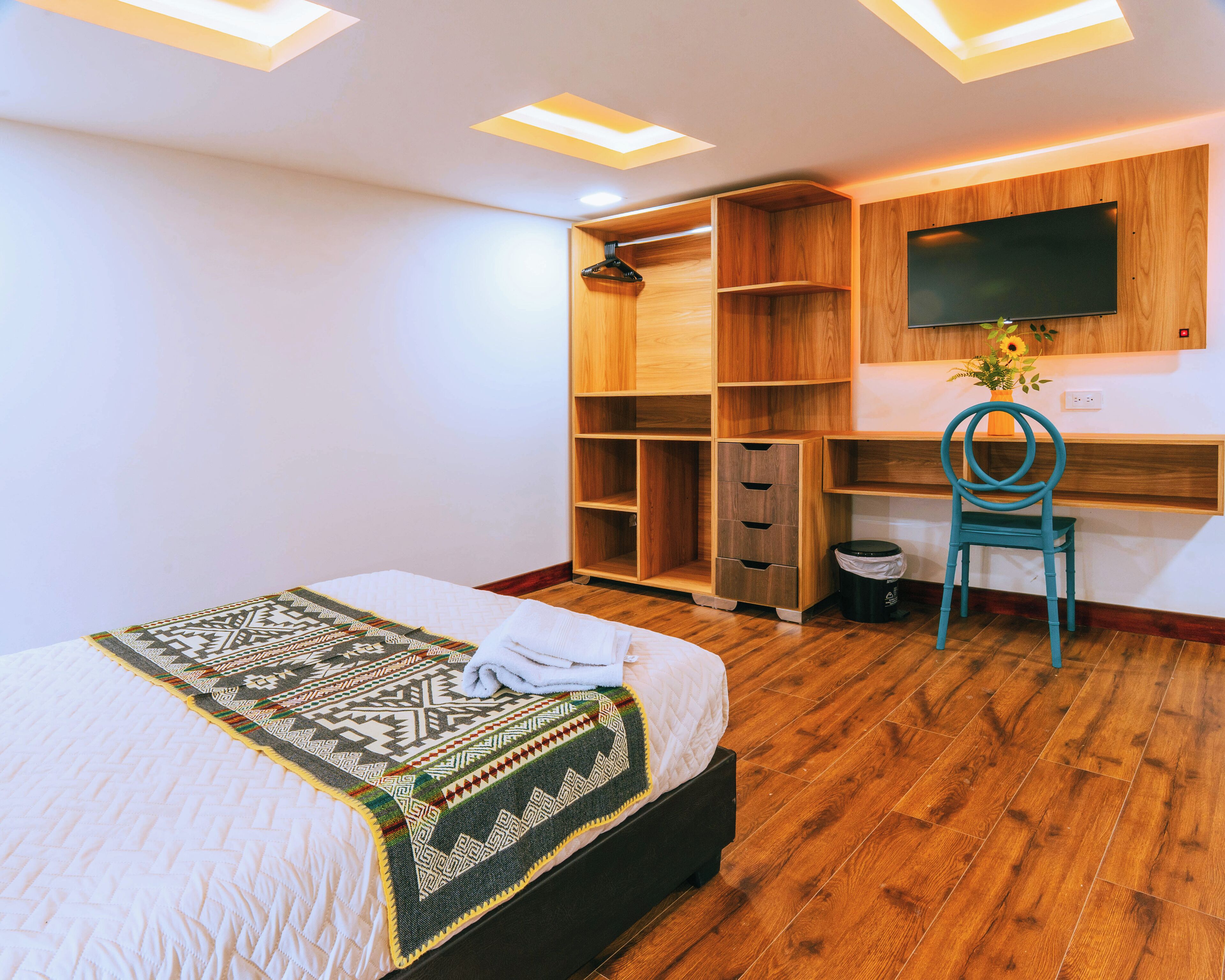 Une chambre à coucher comprenant un lit, un bureau, une chaise et un téléviseur fixé au mur.