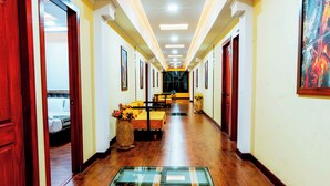 A hotel hallway with wooden flooring, a central glass table, and framed artwork on the walls. - Hotel Casa Santiago (San Juan de Pasto)