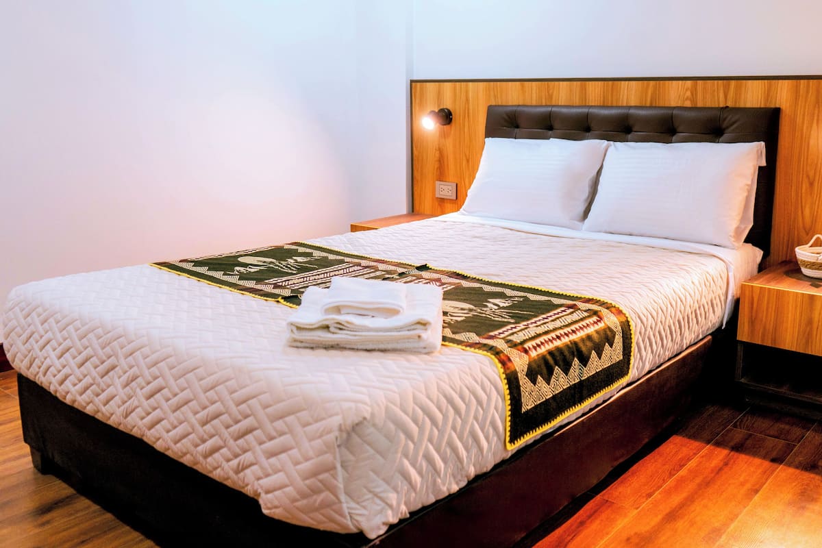 A neatly made bed with a quilted bedspread, a folded towel, and a decorative throw.