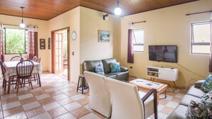Un salon comprenant un canapé, un téléviseur, une table à manger et des chaises.