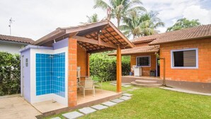 Une maison dotée d’un patio couvert, d’une salle de bain aux carreaux bleus et d’un petit espace extérieur aménagé pour s’asseoir.