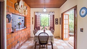 Un coin repas avec un mur en briques, un sol carrelé, une table avec des chaises et une fenêtre avec des rideaux.