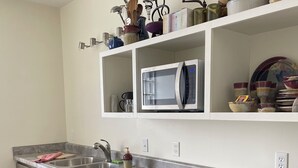 A kitchen with a stainless steel countertop, a microwave, and various kitchen utensils and dishes on shelves. - The Library, 1-queen bed, 1-bedroom apartment in Hannibal awaits your visit. (Hannibal)
