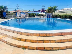 Uma piscina com um deck ladrilhado e degraus para entrar na água.