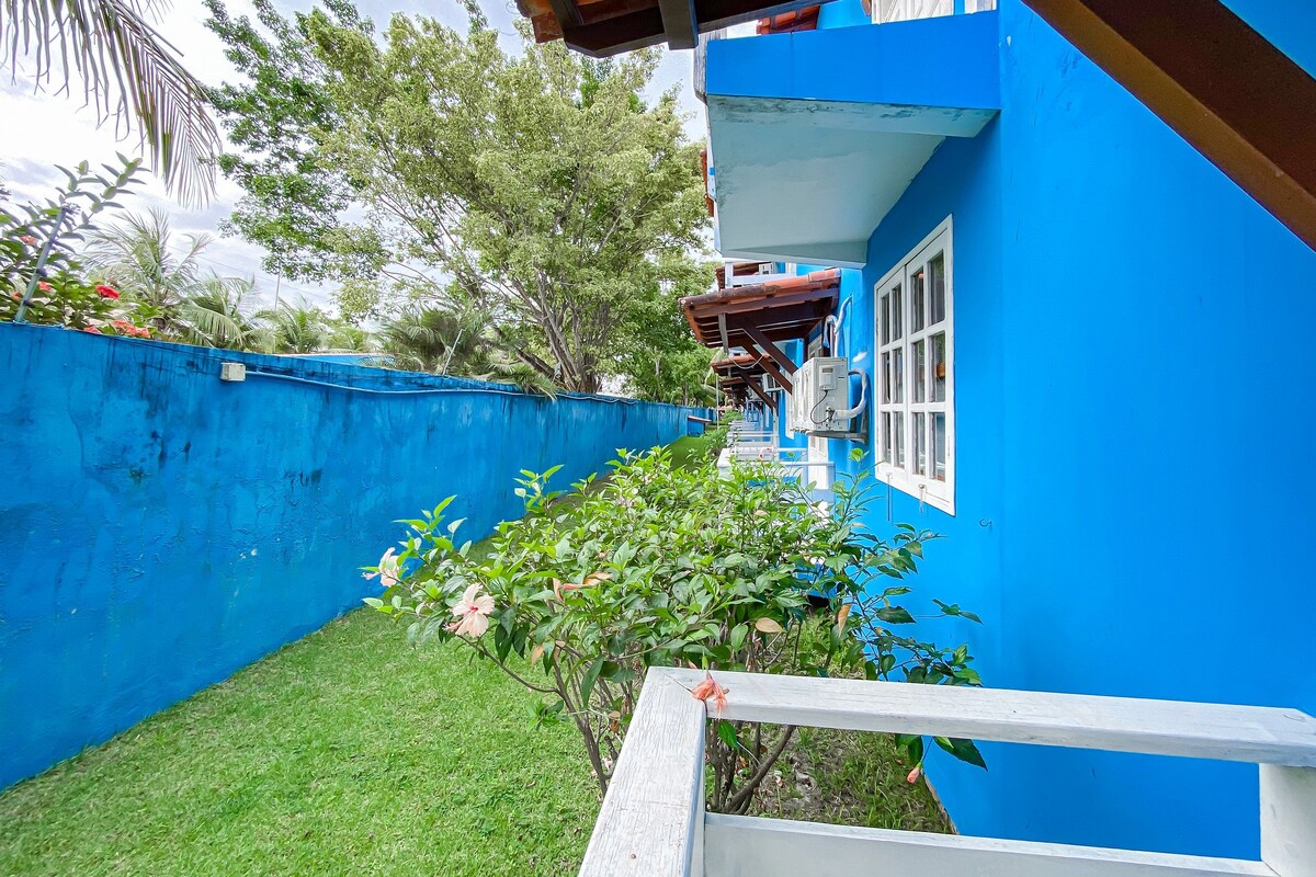 Um edifício azul com janela branca, cerca de madeira e grama verde.