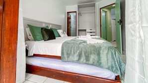 Een slaapkamer met een bed, een kledingkast en een plafondventilator.