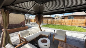 Eine Terrasse im Freien mit überdachter Sitzgruppe, darunter ein Sofa, Stühle und ein Couchtisch.