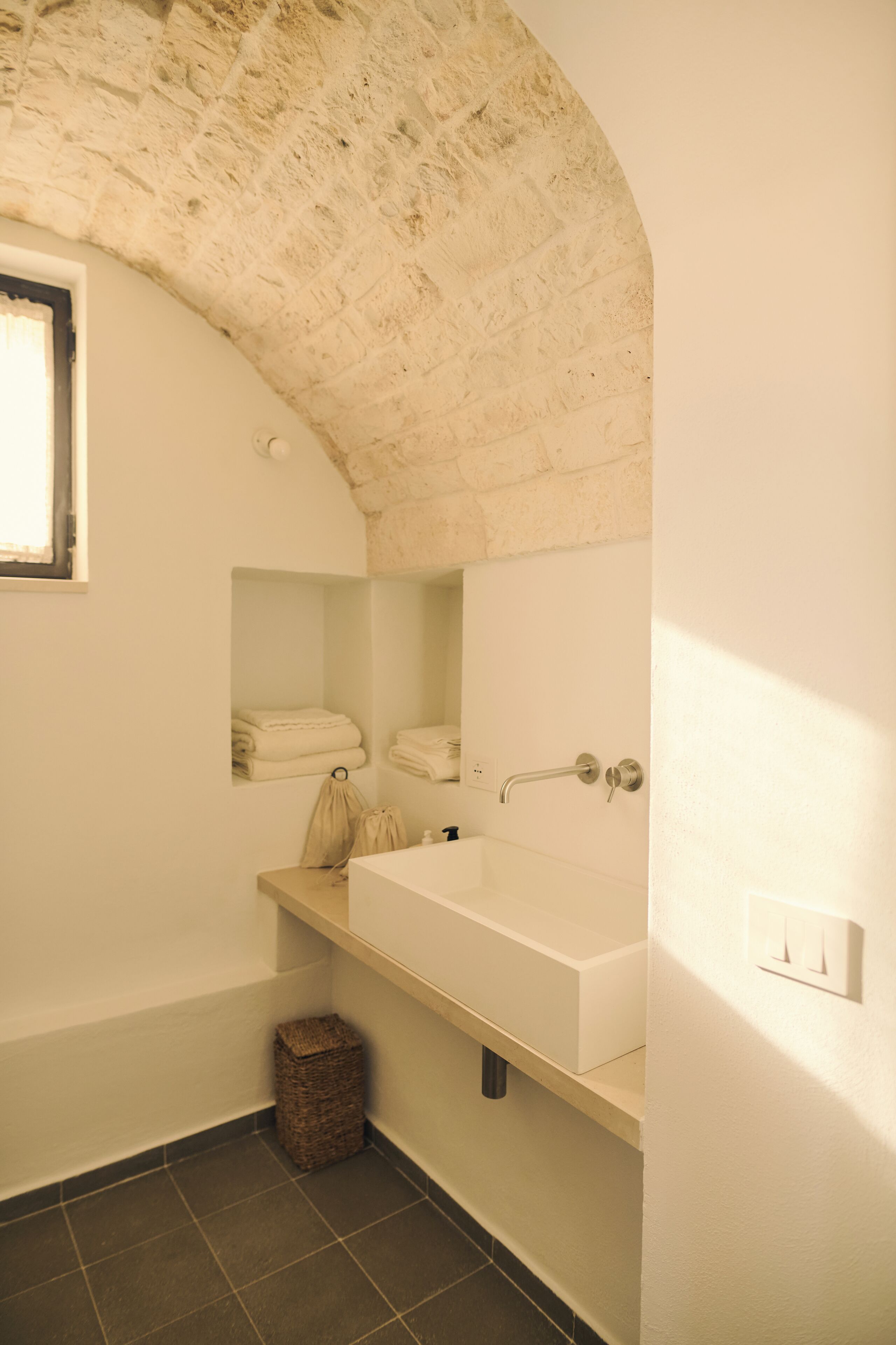 A bathroom with a large bathtub, a towel rack, and a small wicker basket on the floor.