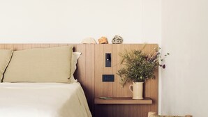 A bedroom with a bed, a small wooden nightstand, a potted plant, and a stool. - Masseria Pietra e Terra  (Carovigno)