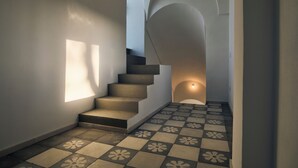 A staircase with a checkered floor pattern, leading to a landing with a light fixture. - Masseria Pietra e Terra  (Carovigno)