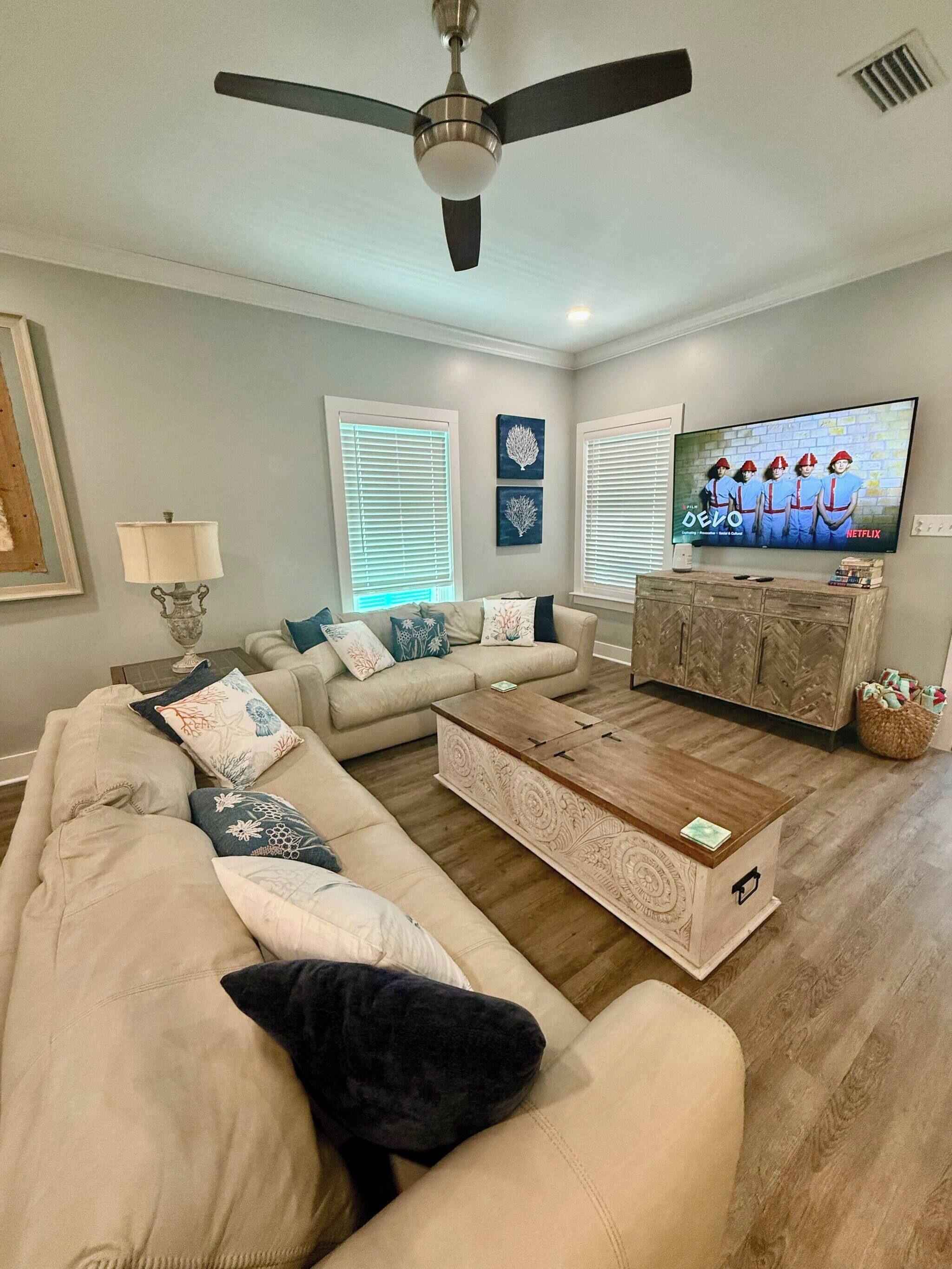 A living room with a beige sofa, a coffee table, and a TV on a wooden cabinet.