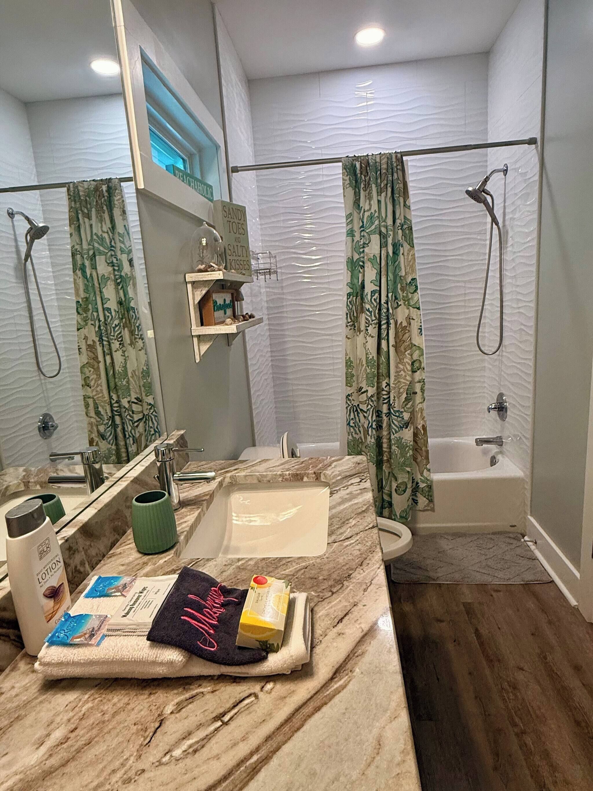 A bathroom with a marble sink, a bathtub, and a shower. There is a shelf with toiletries and a towel rack.