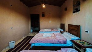 A room with three beds, wooden ceiling beams, and a small trash bin. - Triple Room with Garden View #2 (Marsa Matrouh Governorate)