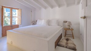 Un dormitorio con una cama grande, una puerta de madera, una mesita con una lámpara y un manto de piel en el suelo.