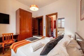 A hotel room with a bed, a desk, a chair, a wardrobe, and a television. - Scorfano Room – Le Chele with Sea View, Wi-Fi, and Air Conditioning (Torre Lapillo)