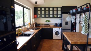 A kitchen with a washing machine, wooden countertop, and cabinets. - Villa da Rochinha - Seaview apartment with jacuzzi (Madeira)