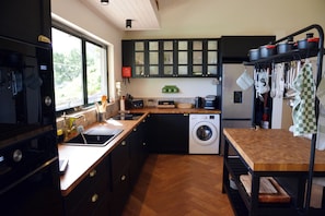 Eine Küche mit Waschmaschine, Holz Arbeitsplatte und Schränken.