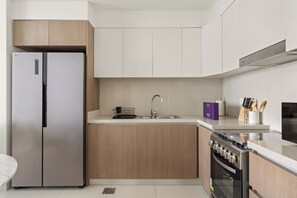 Eine moderne Küche mit einem Edelstahl-Kühlschrank, einem Einbauofen und einer Spüle.