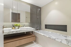 A modern bathroom with a large mirror, two sinks, a shower, and a built-in bench. - Silkhaus The Grand (Dubai)