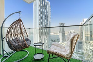 Ein Balkon mit einer Hängematte, einem gepolsterten Sessel und einem kleinen Tisch.