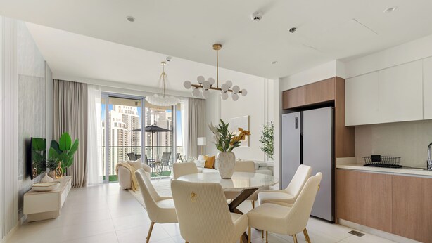 A modern kitchen with a built-in refrigerator and a dining area with a round table and chairs. - Silkhaus The Grand (Dubai)